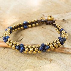 the beaded bracelet is made with gold and blue beads on a piece of wood