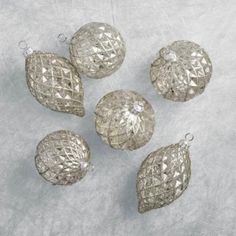 five silver ornaments sitting on top of a white surface