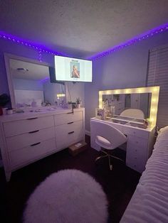 a bedroom with white furniture and purple lights on the ceiling, along with a flat screen tv