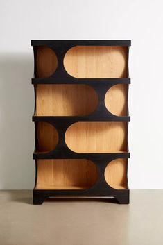 a wooden bookcase with several compartments on the top and bottom, in front of a white wall