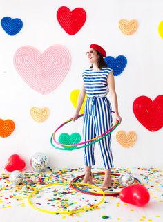 a woman holding a hula hoop in front of colorful balloons and confetti