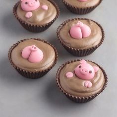 six cupcakes with chocolate frosting and pink pigs on them, sitting next to each other