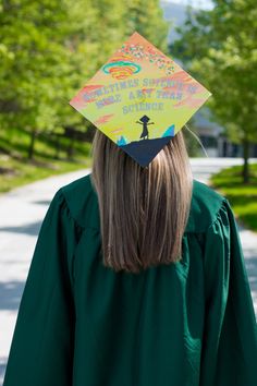 a person with a graduation cap on their head is walking down the street in front of some trees