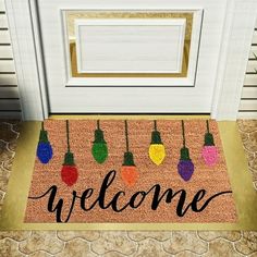 a welcome mat with christmas lights hanging from it's sides on the front door