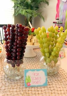 grapes are arranged in vases on a table with other fruit and snacks around them