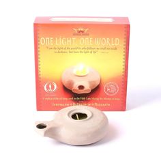 a white ceramic tea light holder next to a box with the candle in it's center