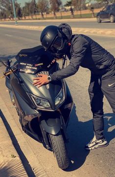 a man in black riding on the back of a silver motorcycle next to a street