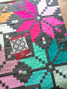 a book is laying on top of a quilted table runner that has been made into a pattern