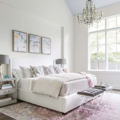 a white bed sitting in a bedroom on top of a pink rug next to a window