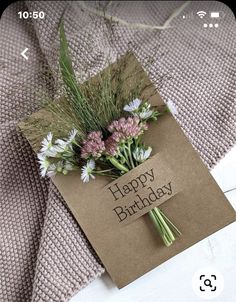 a birthday card with flowers on it sitting on top of a bed next to a pillow