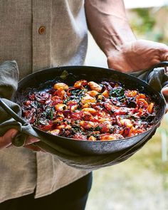 a man is holding a pan full of food