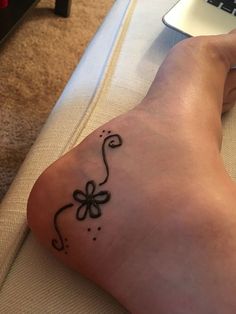 a person's foot with a tattoo on it and a laptop in the background