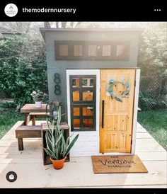 a small house with a potted plant next to it and the door is open