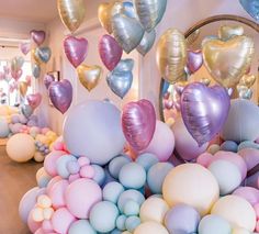 many balloons are floating in the air near a mirror and other decorations on the wall