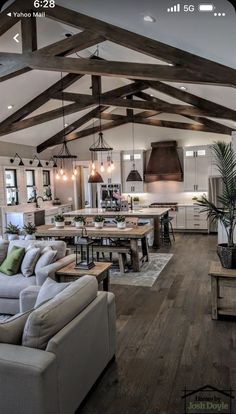 a large open concept kitchen and living room with wood flooring, exposed beams, white walls, and wooden floors