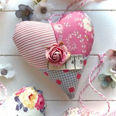 two heart shaped cushions with flowers on them next to each other and measuring tape in the middle