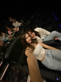 two young women are laying on the seats in an auditorium with their arms around each other