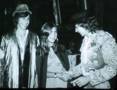 an old black and white photo of two women shaking hands with another woman in the background