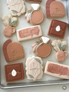 some cookies are on a tray and decorated with different types of icing, including one that says will you marry me?