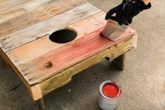 a person holding a paint brush over a wooden table with two buckets on it