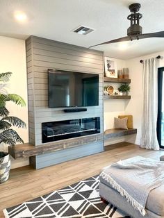 a living room with a large flat screen tv on top of a wall mounted fireplace