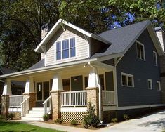 a blue house with white railings and windows on the front porch is surrounded by trees