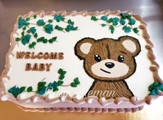 a welcome baby cake is decorated with green leaves and a brown teddy bear on it