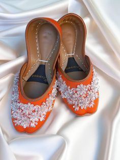 Embrace the whimsy and elegance of our Sunset Brilliance flat shoes, featuring a vibrant orange base adorned with beads, sequins, and intricate wire embellishments in enchanting floral patterns. Whether you call them Punjabi jutti, mojari for women, or women's khussa, these jeweled flats blend timeless allure with a touch of modern flair, making them the perfect choice to elevate any special occasion. Product Details: Base Material: Luxurious orange fabric Embellishments: Beads, sequins, and sil Flat Wedding Shoes With Rhinestones, Crystal Embellished Flats For Wedding, Embellished Flats For Wedding, Elegant Flats With Round Toe For Reception, Elegant Round Toe Flats For Reception, Embellished Flat Heel Wedding Shoes, Elegant Festive Flats With Round Toe, Formal Flats For Festivals With Round Toe, Elegant Flats With Round Toe For Festive Occasions