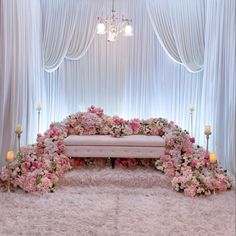 a white couch sitting under a chandelier covered in flowers