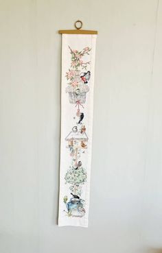 a white wall hanging with birds and flowers on it