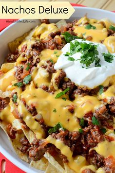 a bowl filled with nachos topped with cheese and sour cream on the top