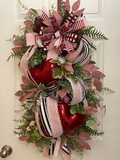 a wreath with two red apples and ribbons hanging on the front door for valentine's day