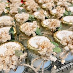 many small jars with flowers in them sitting on a table