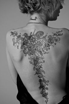 the back of a woman's body with tattoos on her upper and lower back