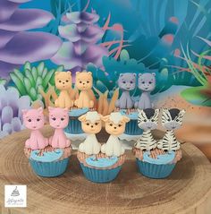 cupcakes with animals on them are sitting on a tree stump in front of an underwater scene