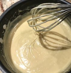 a whisk is being stirred in a black bowl with some cream on it