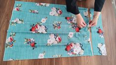 a woman is cutting fabric with scissors on the floor next to a piece of cloth