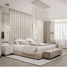 a large white bed sitting in a bedroom under a chandelier