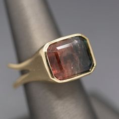 This knockout of a ring is all about that gemmy stone! The tourmaline is an emerald cut measuring 14.30mm x 12.07mm and 9.93mm in depth, weighing 13.08ct. This juicy stone looks slightly more pink in person vs. the warmer color in the photos. It's set in a thick bezel covering the sides and the shank is split at the base to provide stability for the ring. It is also made in a Euro shank design. The ring is crafted in solid 14k and weighs a hefty 16.06g. The ring is currently a size 8.5 and can b Modern Tourmaline Emerald Ring, Watermelon Tourmaline, Bezel Setting, Emerald Cut, Statement Ring, Warm Colors, Tourmaline, Statement Rings, Watermelon