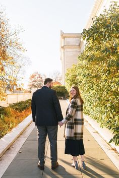 a man and woman walking down a sidewalk holding hands