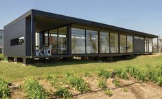 a black house sitting on top of a lush green field next to tall buildings with windows