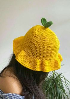 a woman wearing a yellow crocheted hat with a green leaf