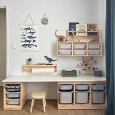 a white desk topped with lots of bins next to a wooden shelf filled with books