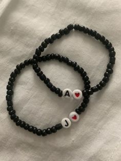 two black beaded bracelets with white and red hearts