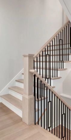 a white staircase with black railing and wooden handrail