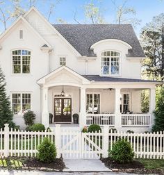 a large white house with two story windows and a black door on the front porch