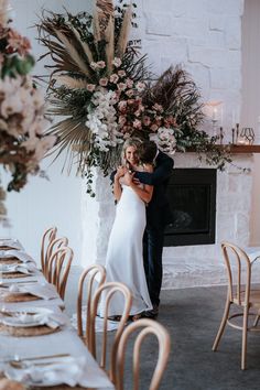 a bride and groom hugging each other in front of the fireplace at their wedding reception