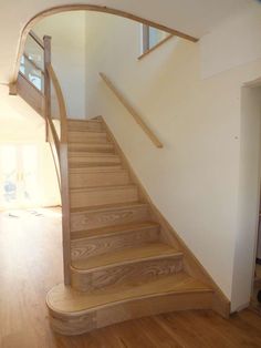 a wooden stair case in an empty room with hard wood flooring and white walls