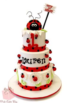 a three tiered cake with ladybug decorations on it's sides and the number one on top