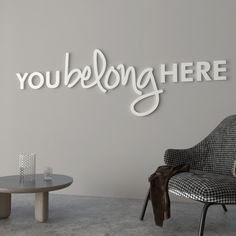 a room with a chair, table and wall sign that says you belong here on it